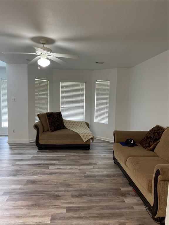 a living room with furniture ceiling fan and a wooden floor