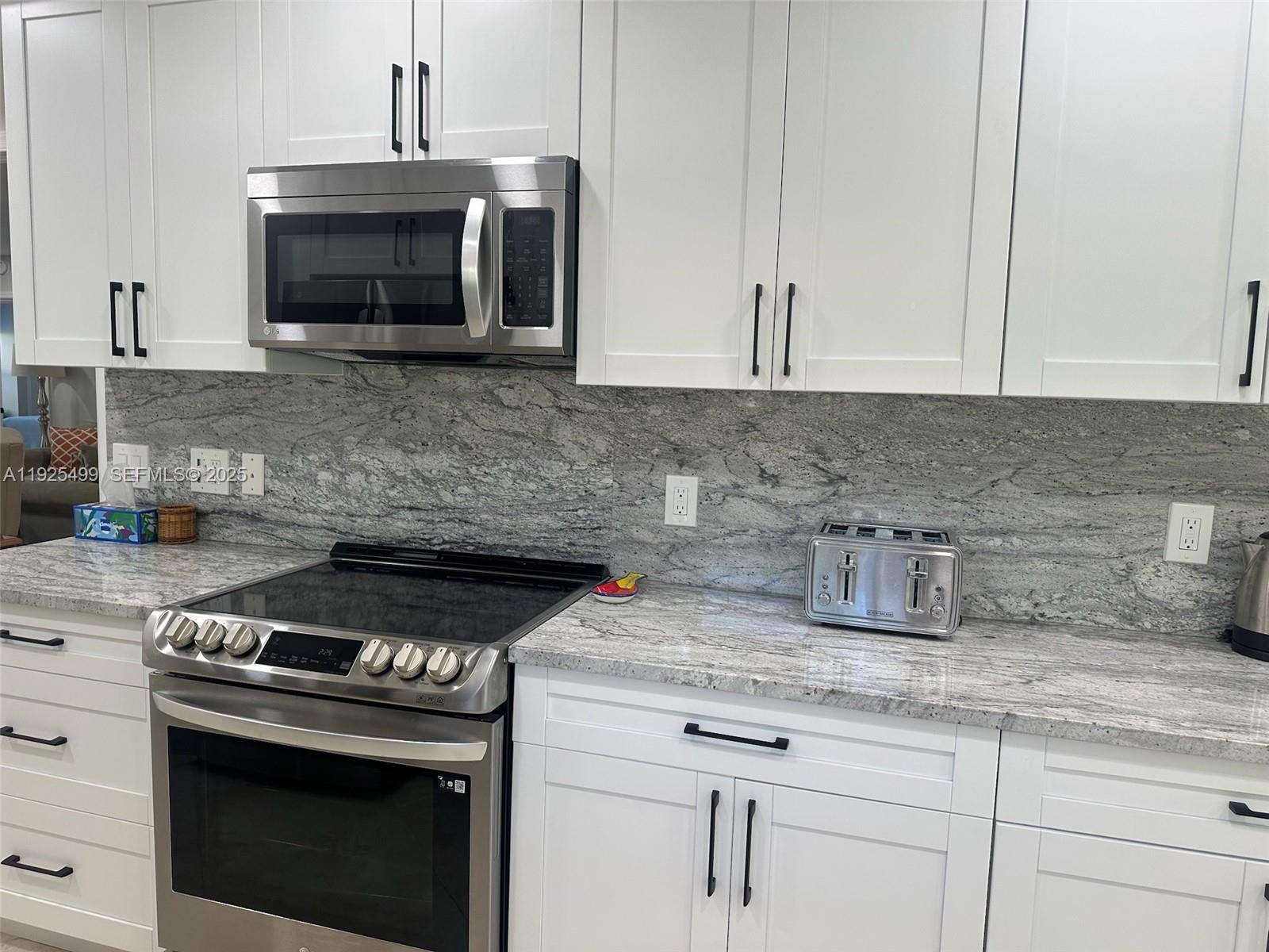 4161 South Us Highway, Unit G2 Jupiter, FL 33477 - Photo 28 of 62 a kitchen with granite countertop a stove top oven microwave and cabinets