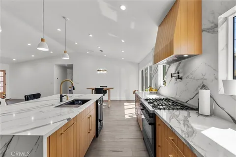 a kitchen with stainless steel appliances granite countertop a sink a stove and a wooden floors