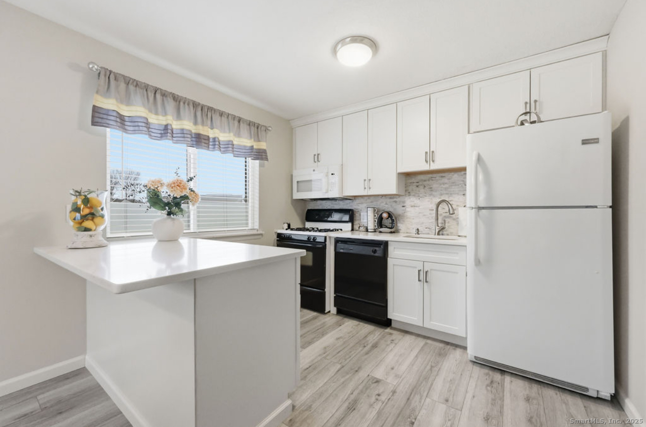 39 Cottonwood Road, Unit 39 Newington, CT 06111 - Photo 4 of 21 a kitchen with a refrigerator a stove a sink and white cabinets