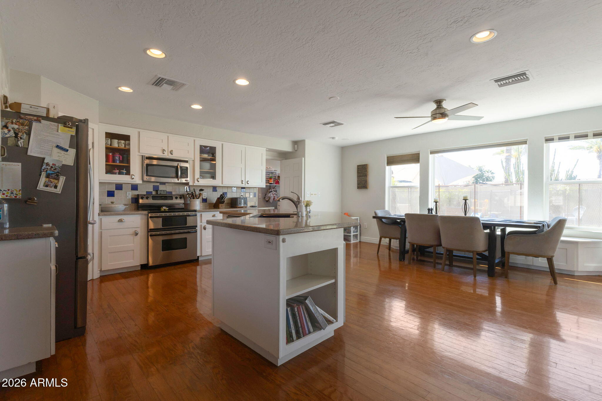 4546 North 34th Place Phoenix, AZ 85018 - Photo 9 of 29 a kitchen with stainless steel appliances granite countertop a stove top oven a sink dishwasher a dining table and chairs with wooden floor