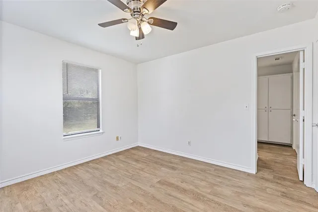 an empty room with wooden floor a ceiling fan and windows