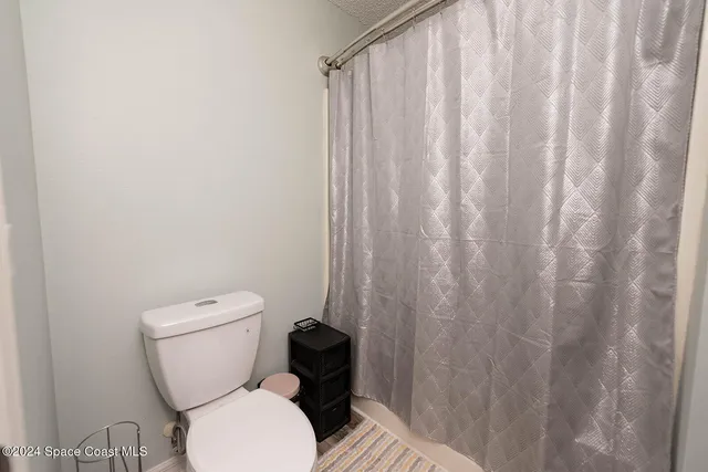 a toilet sitting next to a shower curtain