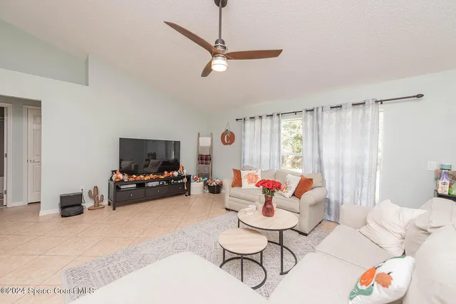 a living room with furniture a flat screen tv and kitchen view