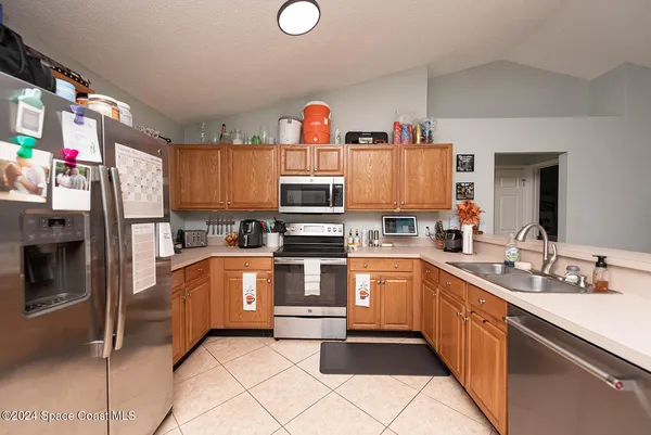 a kitchen with stainless steel appliances kitchen island granite countertop a refrigerator and a sink