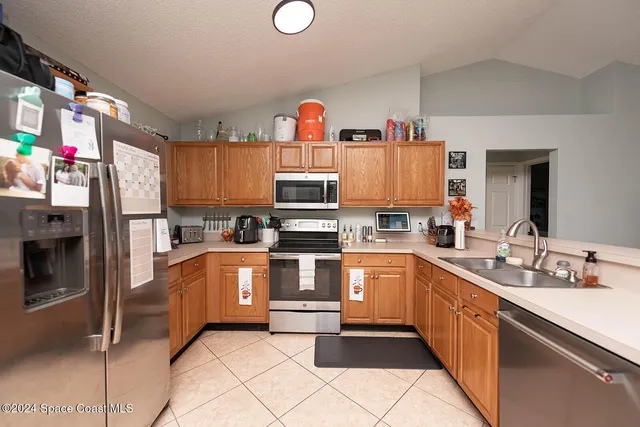 a kitchen with stainless steel appliances kitchen island granite countertop a refrigerator and a sink