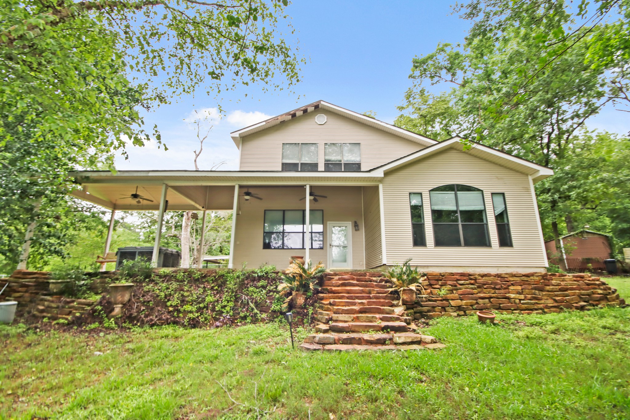 35 Susan Drive Cleveland, TX 77327 - Photo 2 of 33 Charming two-story home with a spacious back porch, set on a lush green lot. Features include large windows, a stone pathway, and a peaceful natural setting. Perfect for enjoying outdoor living.