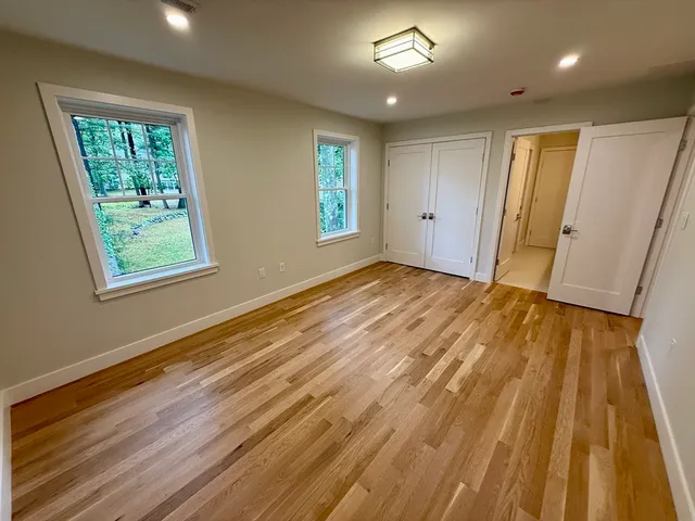 an empty room with wooden floor cabinet and windows