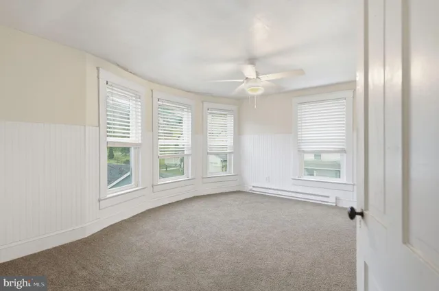 an empty room with windows and fan