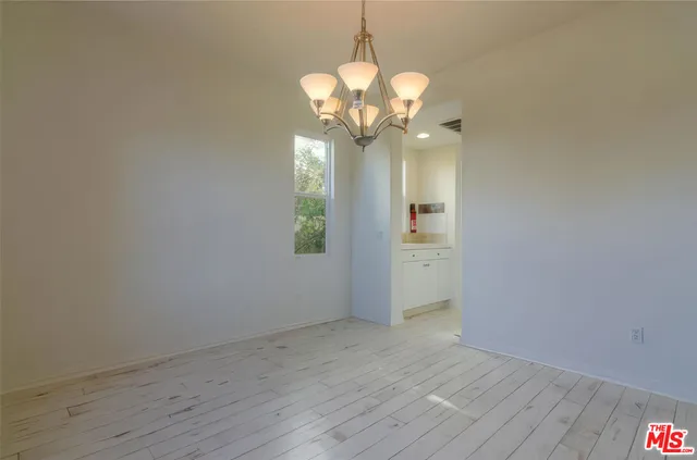 a view of a chandelier in big room with wooden floor