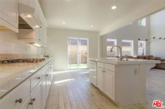 a large kitchen with a lot of counter space and wooden floor