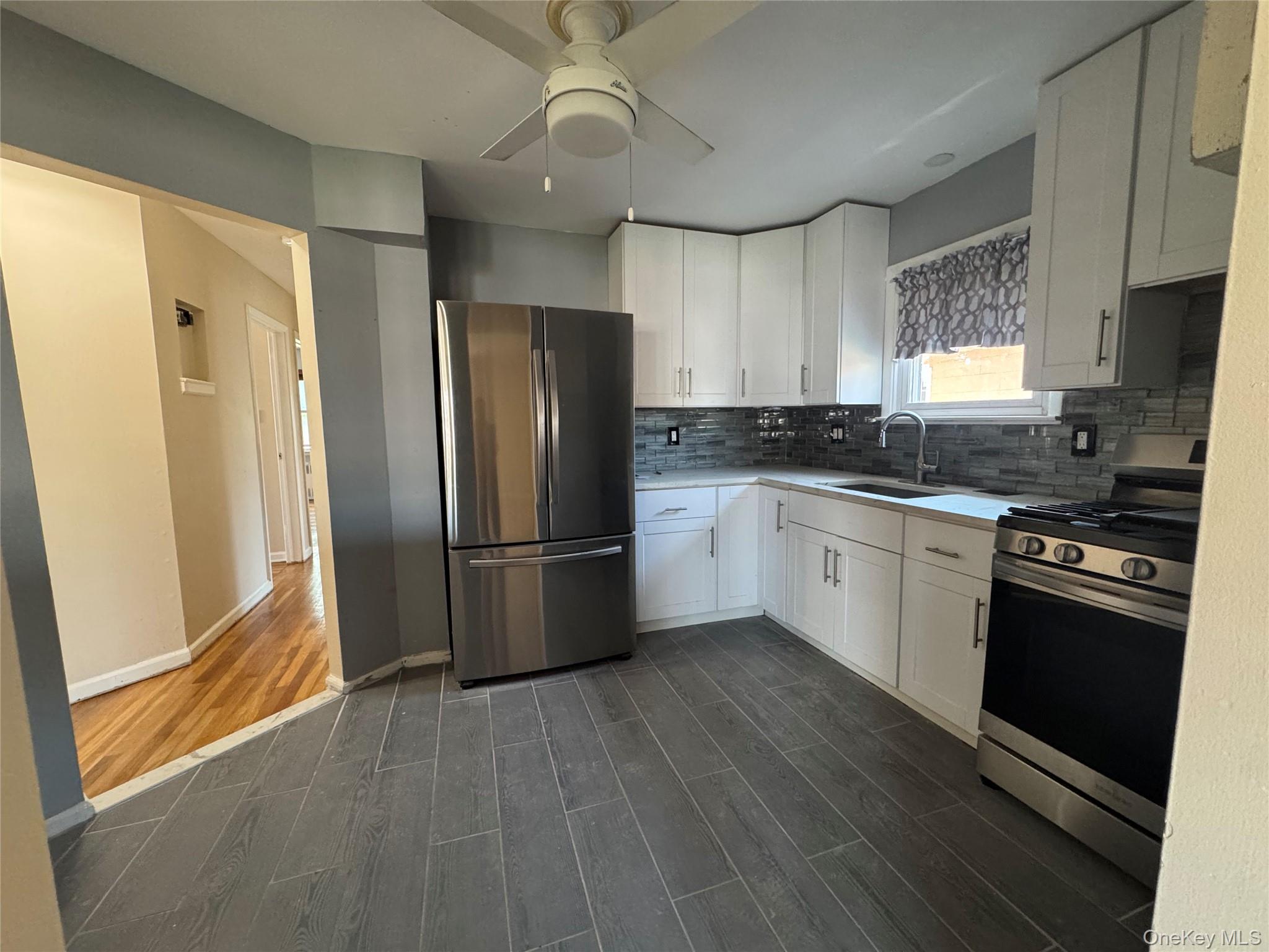 375 Cochran Place, Unit 2 Valley Stream, NY 11581 - Photo 4 of 12 a kitchen with granite countertop a refrigerator a sink a stove and white cabinets
