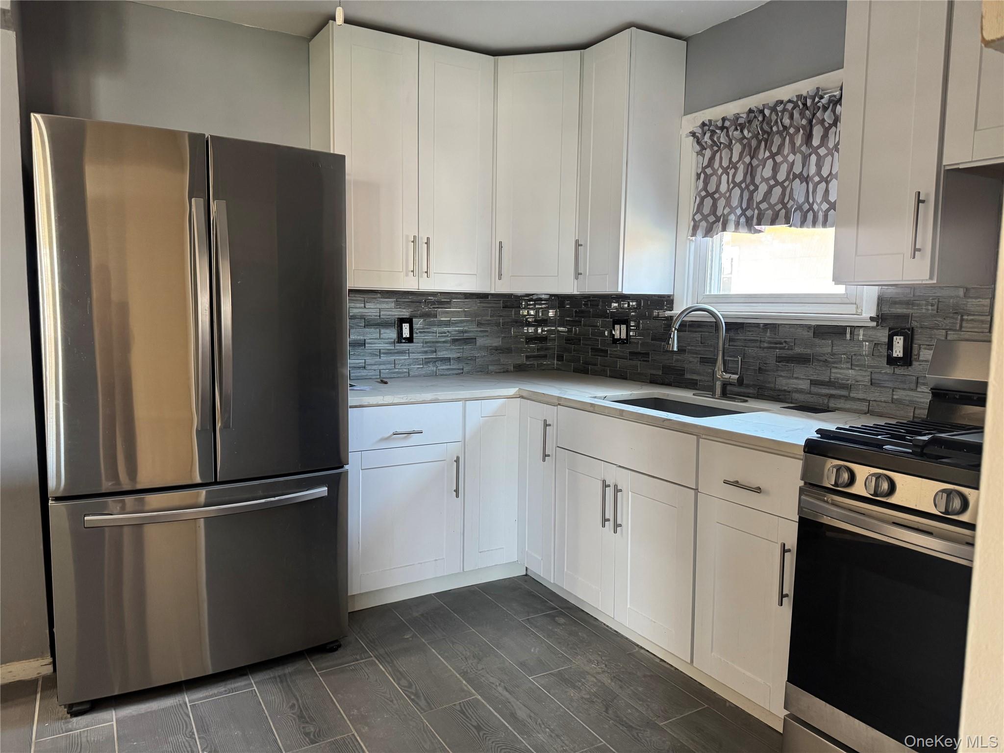 375 Cochran Place, Unit 2 Valley Stream, NY 11581 - Photo 5 of 12 a kitchen with granite countertop stainless steel appliances a refrigerator a sink and cabinets