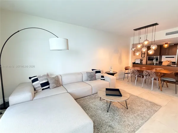 a living room with furniture a dining table and a chandelier