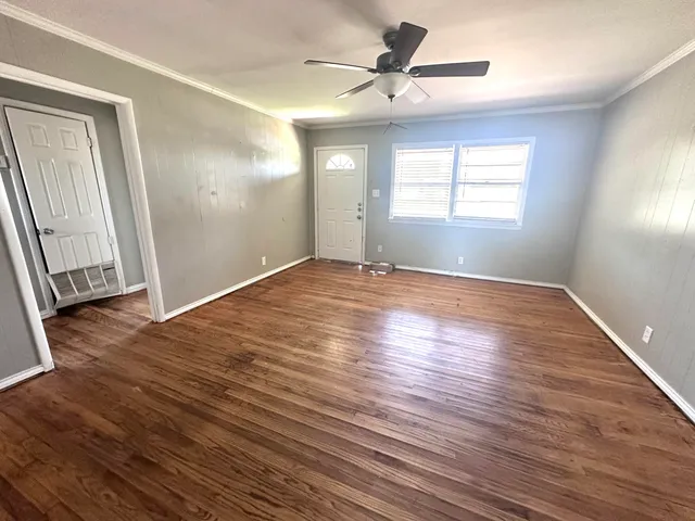 an empty room with wooden floor fan and windows