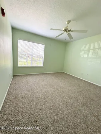 an empty room with a ceiling fan and window