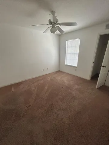 an empty room with windows and fan