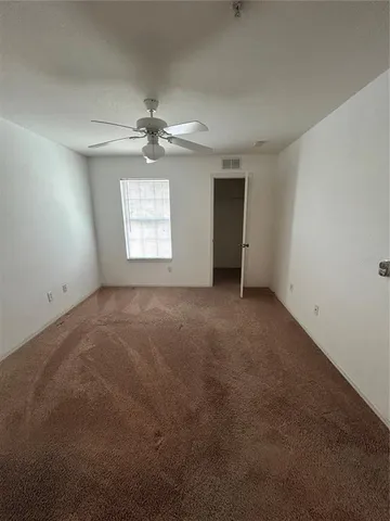 an empty room with a chandelier fan and windows