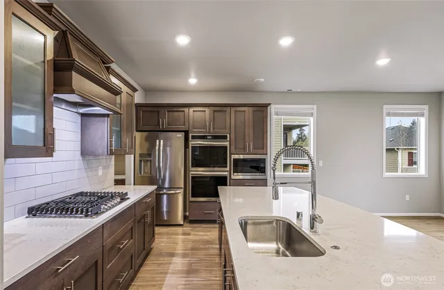 a kitchen with stainless steel appliances granite countertop a sink a stove and a refrigerator