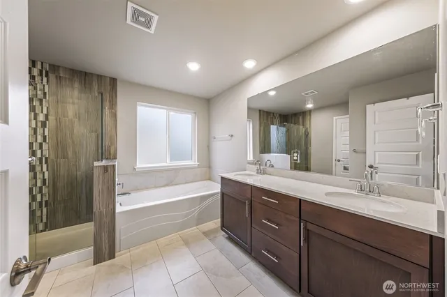 a spacious bathroom with a tub sink shower and mirror