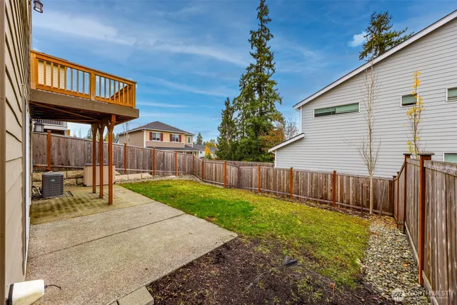 a view of backyard with large trees and wooden fence