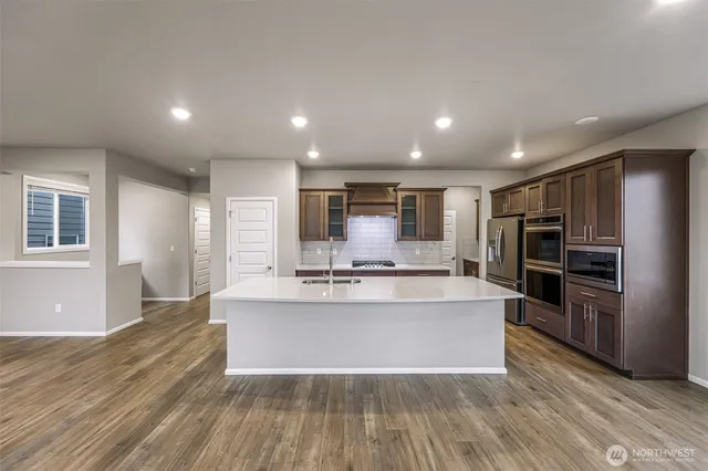 a large white kitchen with kitchen island a stove a refrigerator cabinets and living room view