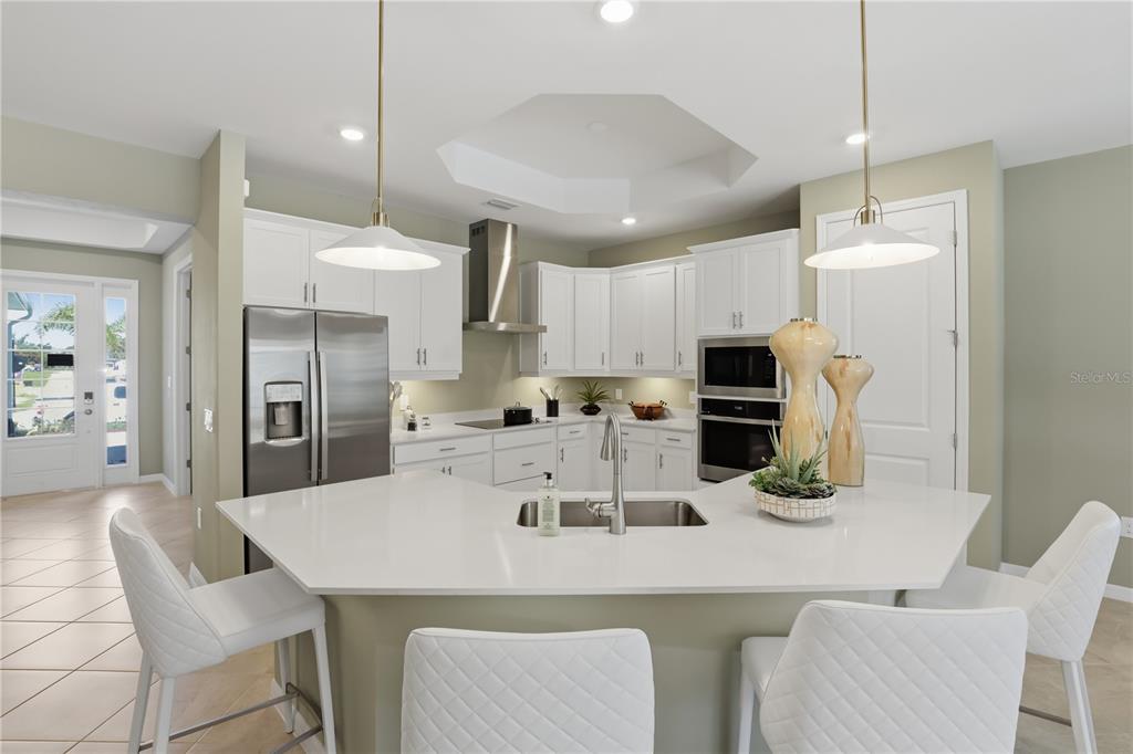 7153 Inlet Isles Lakewood Ranch, FL 34202 - Photo 8 of 26 a kitchen with stainless steel appliances kitchen island granite countertop a dining table chairs refrigerator and microwave