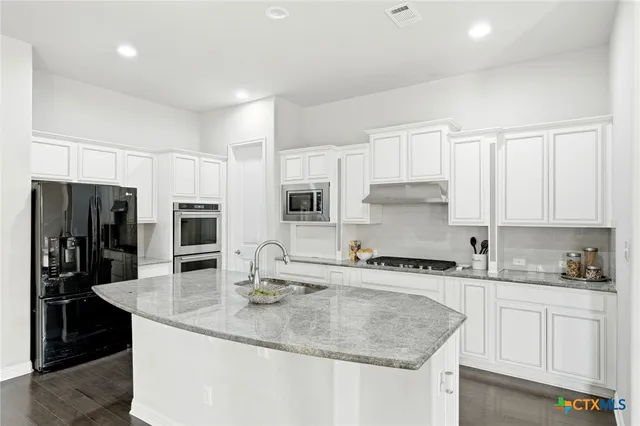 a kitchen with granite countertop white cabinets and stainless steel appliances