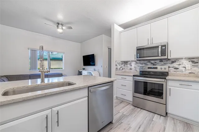 a kitchen with granite countertop a sink stainless steel appliances and cabinets
