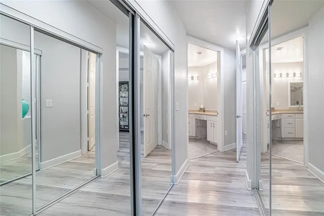 a view of a hallway with wooden floor and a bathroom