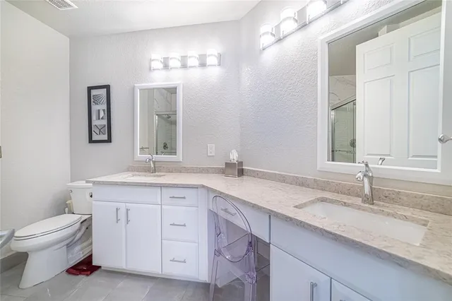 a bathroom with a granite countertop sink a toilet and a mirror