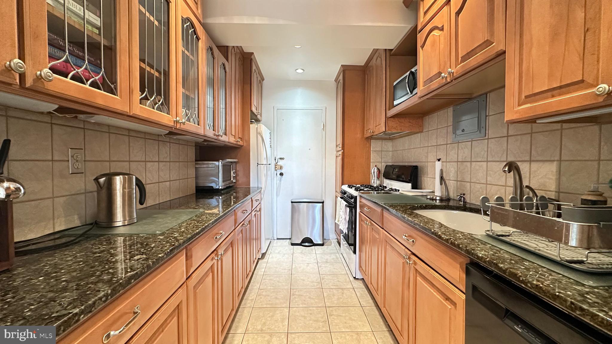 4201 Cathedral Avenue Northwest, Unit 1121E Washington, DC 20016 - Photo 14 of 25 a large kitchen with granite countertop a sink and cabinets