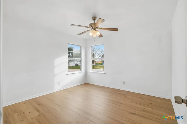 an empty room with windows and fan