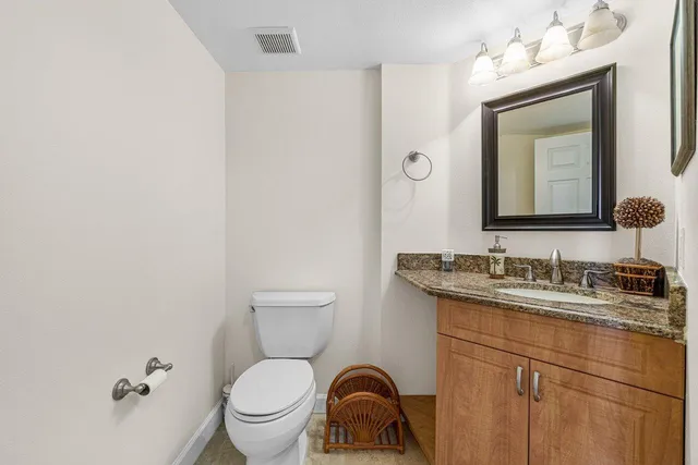 a bathroom with a toilet sink vanity and mirror