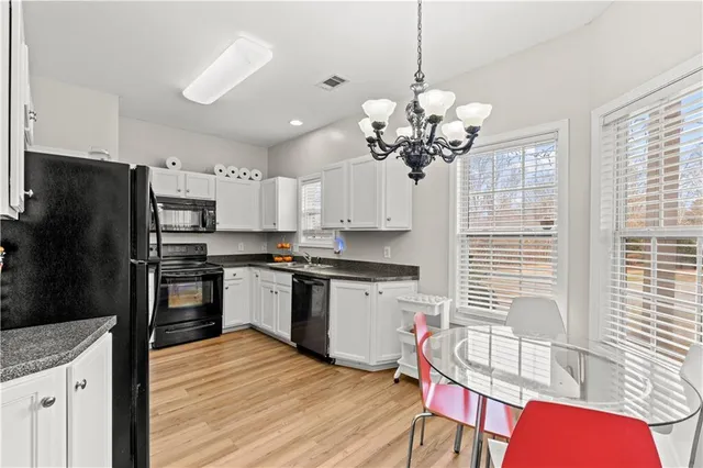 a kitchen with stainless steel appliances granite countertop a dining table chairs sink refrigerator and microwave
