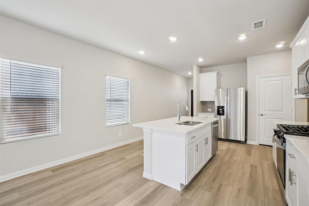 832 Sunflower Road Lavon, TX 75166 - Photo 10 of 39 a large white kitchen with stainless steel appliances granite countertop a stove a sink a refrigerator and white cabinets with wooden floor