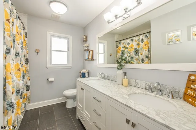 a bathroom with a granite countertop double vanity sink mirror and a toilet