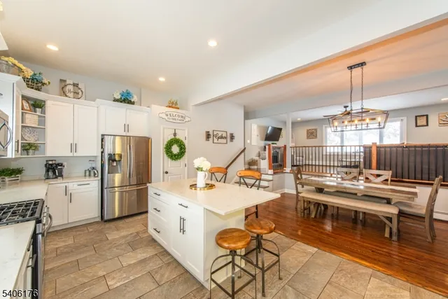 a kitchen with stainless steel appliances kitchen island granite countertop a refrigerator oven a sink dishwasher and white cabinets with wooden floor