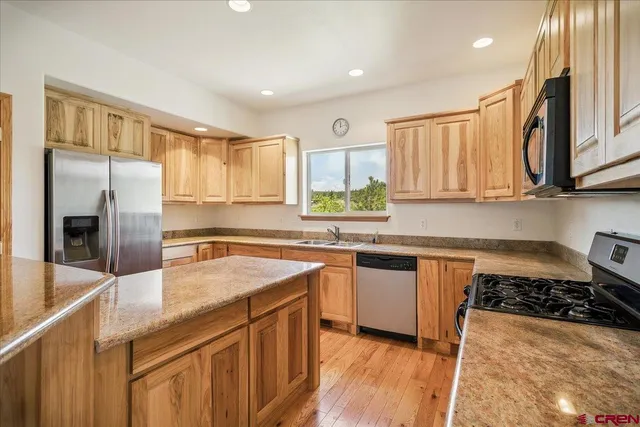 a kitchen with stainless steel appliances a sink a stove a refrigerator and cabinets