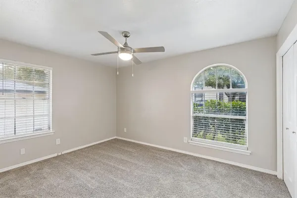 an empty room with ceiling fan and windows