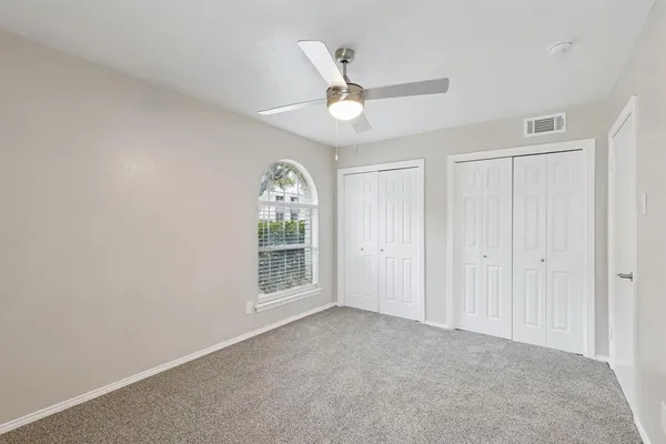 an empty room with windows and fan