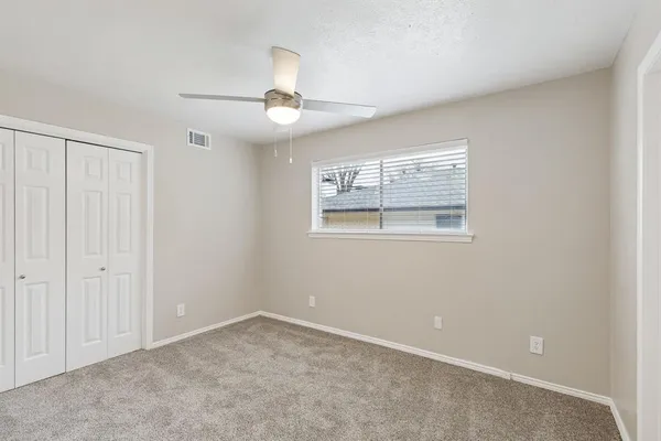an empty room with windows and fan