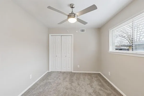 an empty room with a window and a fan