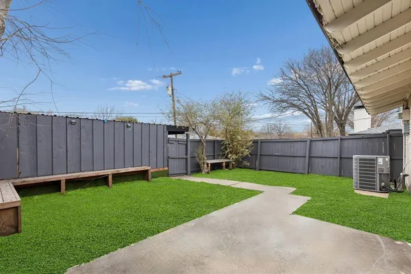 a view of a backyard with potted plants and large tree