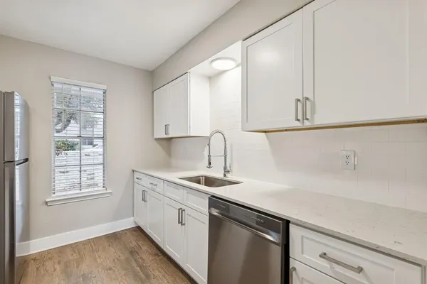 a view with granite countertop a sink white cabinets and a wooden floor