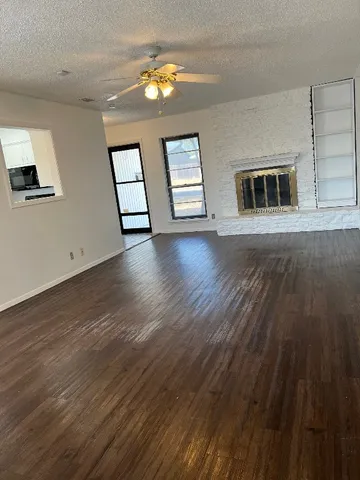 a view of an empty room with window and wooden floor