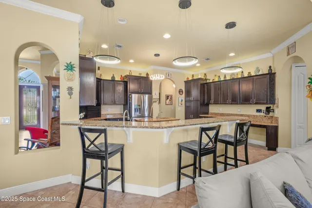 a kitchen with stainless steel appliances kitchen island granite countertop a refrigerator a stove and a dining table with wooden floor