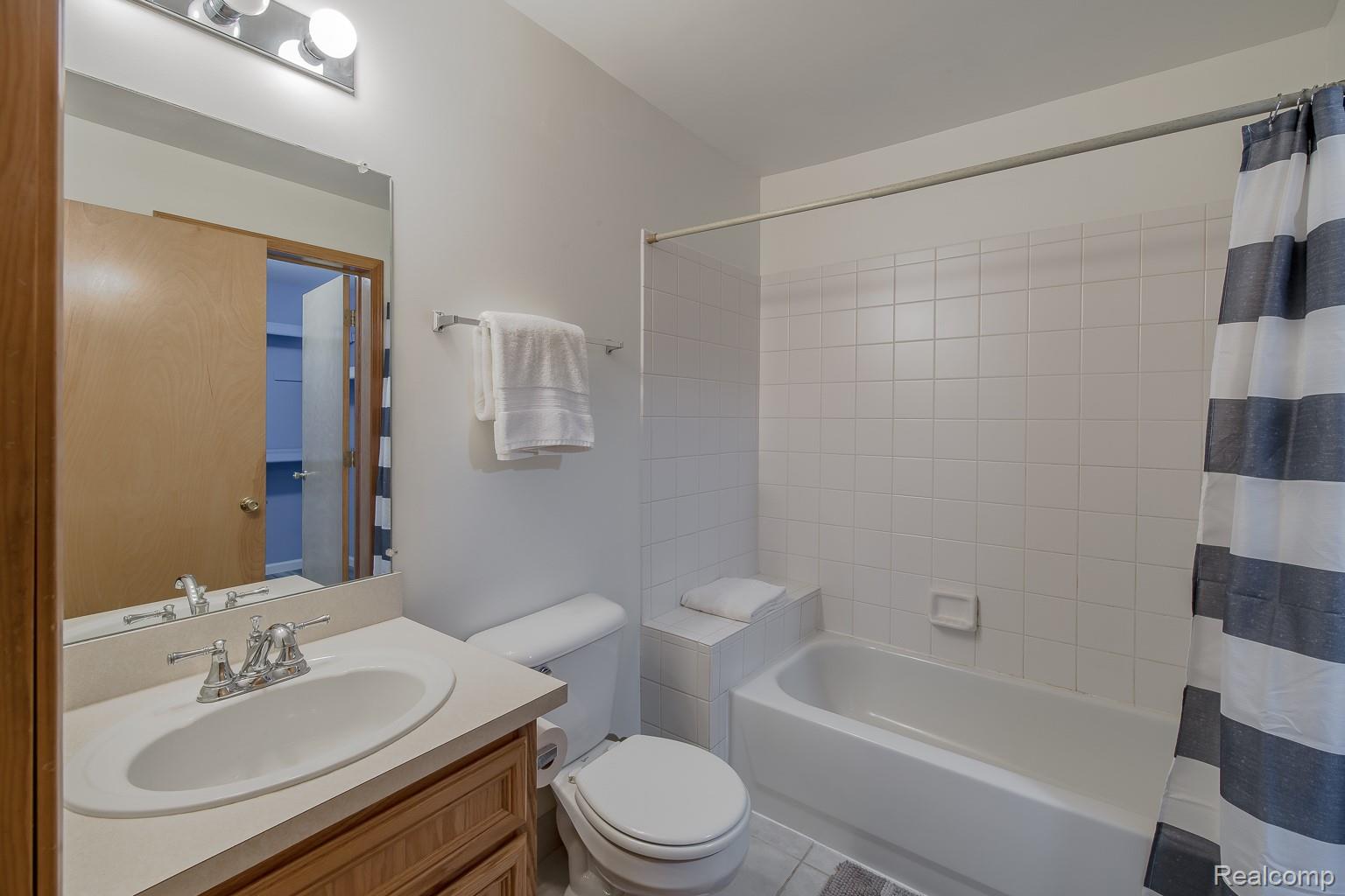 2154 Frazho Road Warren, MI 48091 - Photo 21 of 36 Bathroom featuring a vanity with an integrated sink, a full-width mirror, a three-bulb light fixture, a toilet, and a tiled bathtub/shower combination