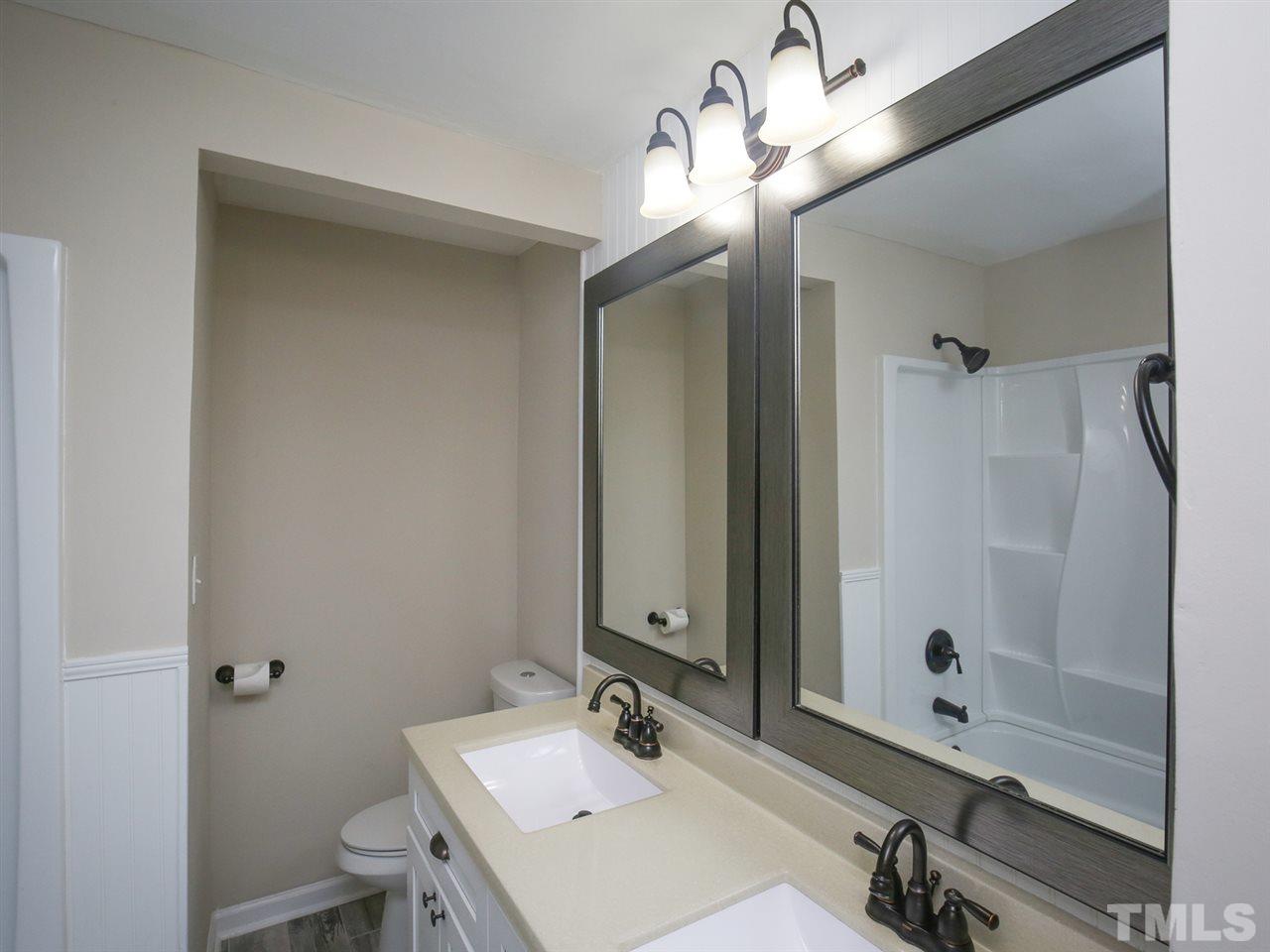 312 Colleton Road Raleigh, NC 27610 - Photo 9 of 25 a bathroom with a sink a light fixture and a glass door shower