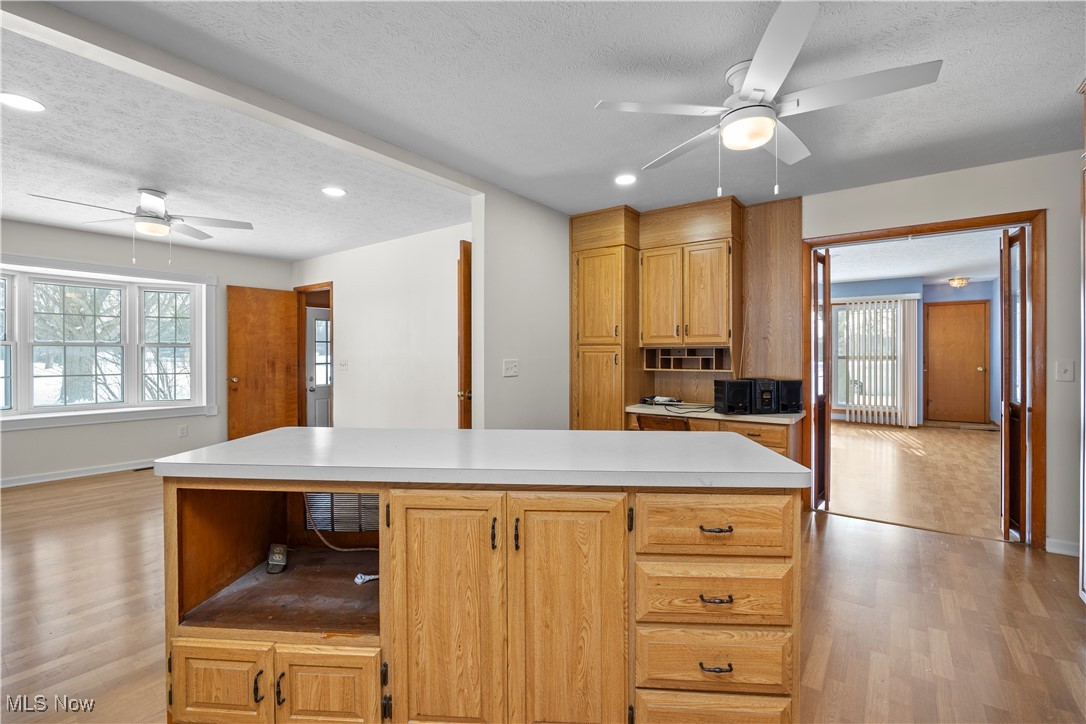 14015 West Lake Road Vermilion, OH 44089 - Photo 18 of 50 Kitchen with ceiling fan, a kitchen island, light wood finished floors, light countertops, and a textured ceiling